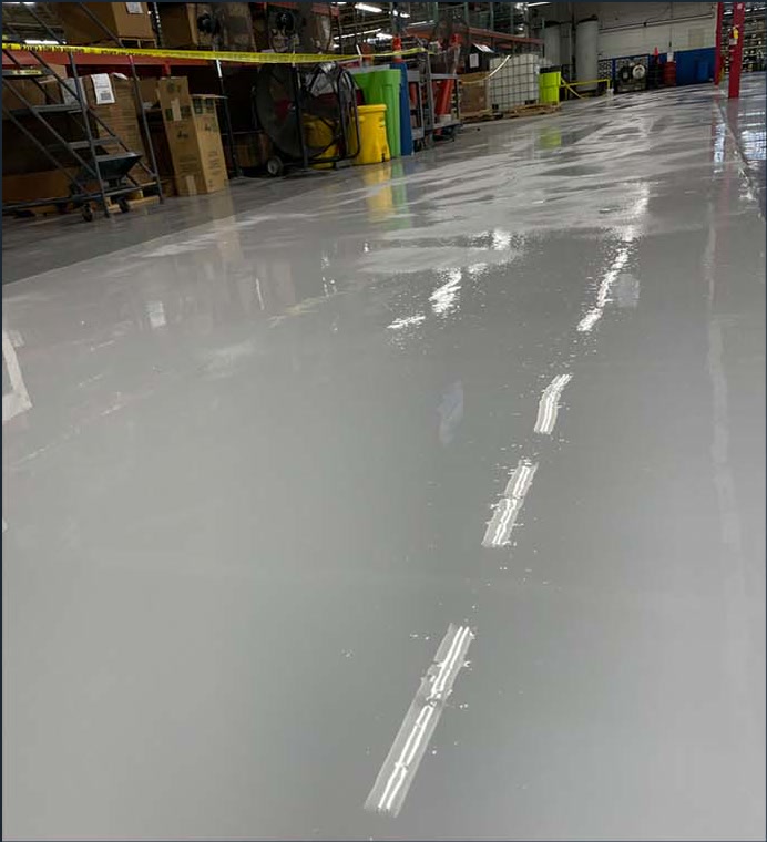 Glossy gray coated floor across a commercial warehouse