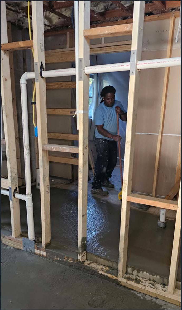 Framed interior work area with visible plumbing and a worker