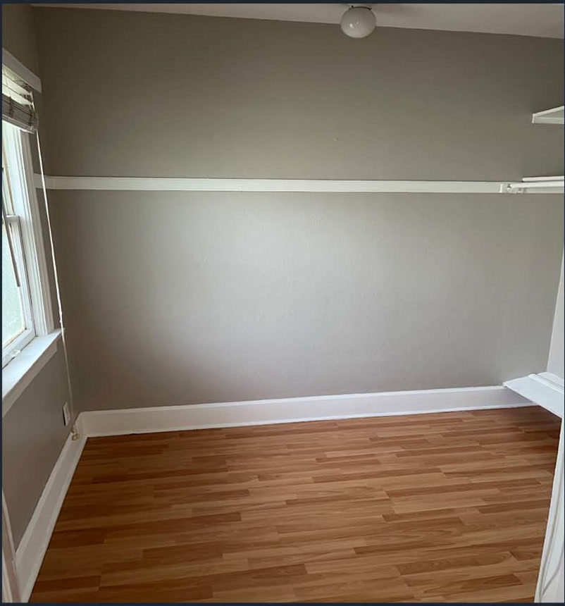 Finished room with a window, painted walls, and wood-look flooring